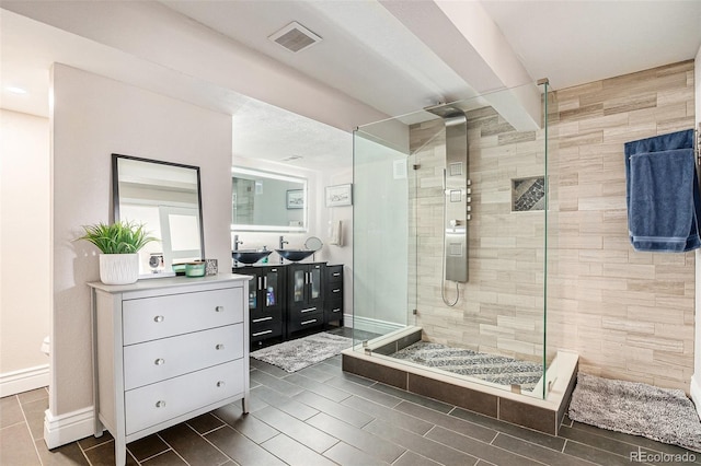 bathroom featuring a stall shower, baseboards, visible vents, and vanity