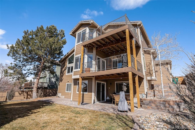 rear view of property with a patio, a lawn, fence, and a balcony