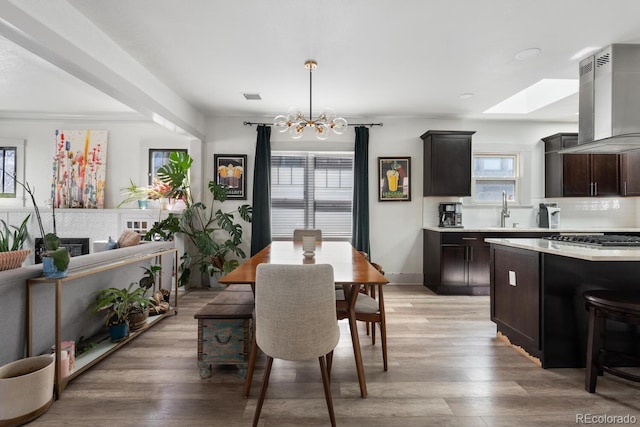561 Cook St, Denver, CO 80206 - dining room featuring a skylight, a chandelier, and light wood-type flooring