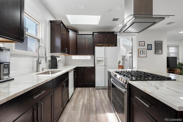 561 Cook St, Denver, CO 80206 - kitchen with white appliances, a sink, a skylight, island range hood, and healthy amount of natural light