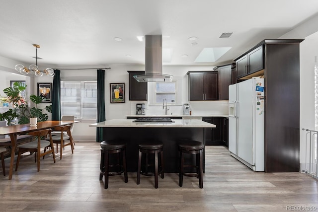 561 Cook St, Denver, CO 80206 - kitchen featuring white refrigerator with ice dispenser, island exhaust hood, light countertops, a kitchen island, and a skylight