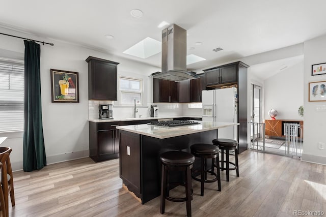 561 Cook St, Denver, CO 80206 - kitchen with island exhaust hood, gas stovetop, light wood-type flooring, a skylight, and recessed lighting