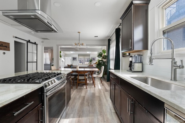 561 Cook St, Denver, CO 80206 - kitchen featuring gas stove, a sink, a barn door, light wood finished floors, and light stone countertops