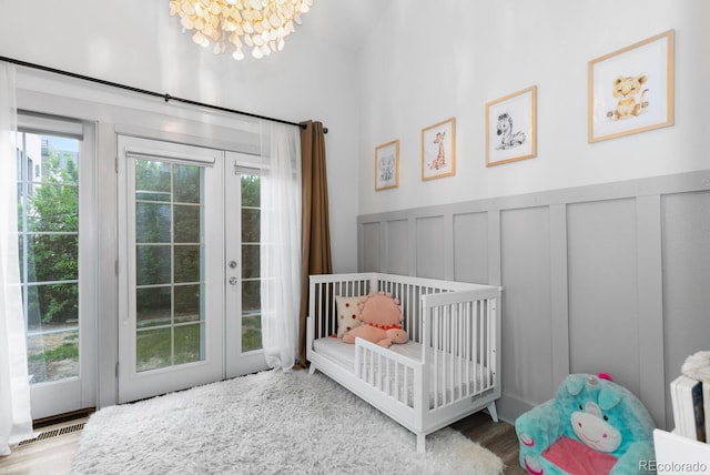 561 Cook St, Denver, CO 80206 - bedroom featuring a chandelier, french doors, a decorative wall, wood finished floors, and wainscoting