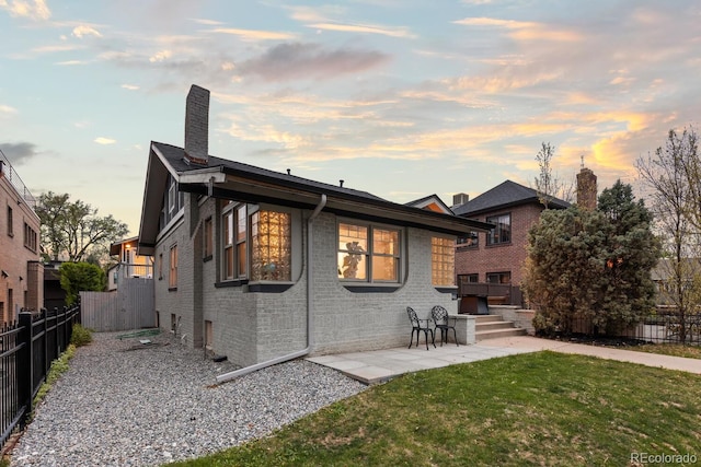 561 Cook St, Denver, CO 80206 - back of property at dusk with brick siding, a patio area, and a chimney
