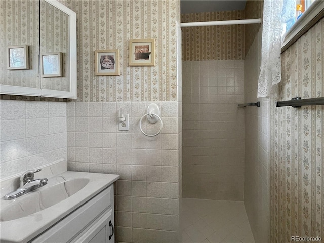 6236 Ingalls Ct, Arvada, CO 80003 - bathroom featuring wallpapered walls, a tile shower, vanity, tile walls, and wainscoting