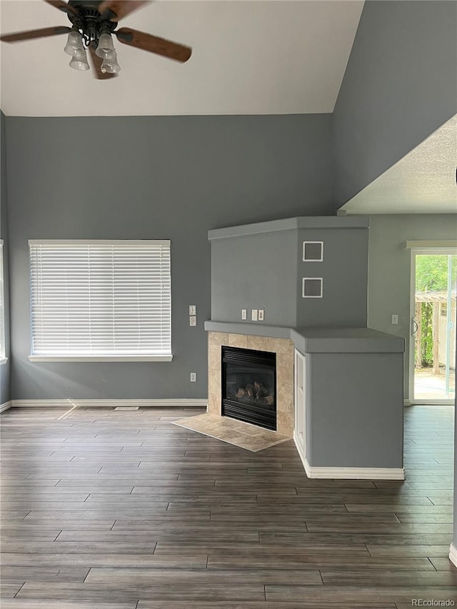 unfurnished living room with ceiling fan, a tile fireplace, and hardwood / wood-style floors