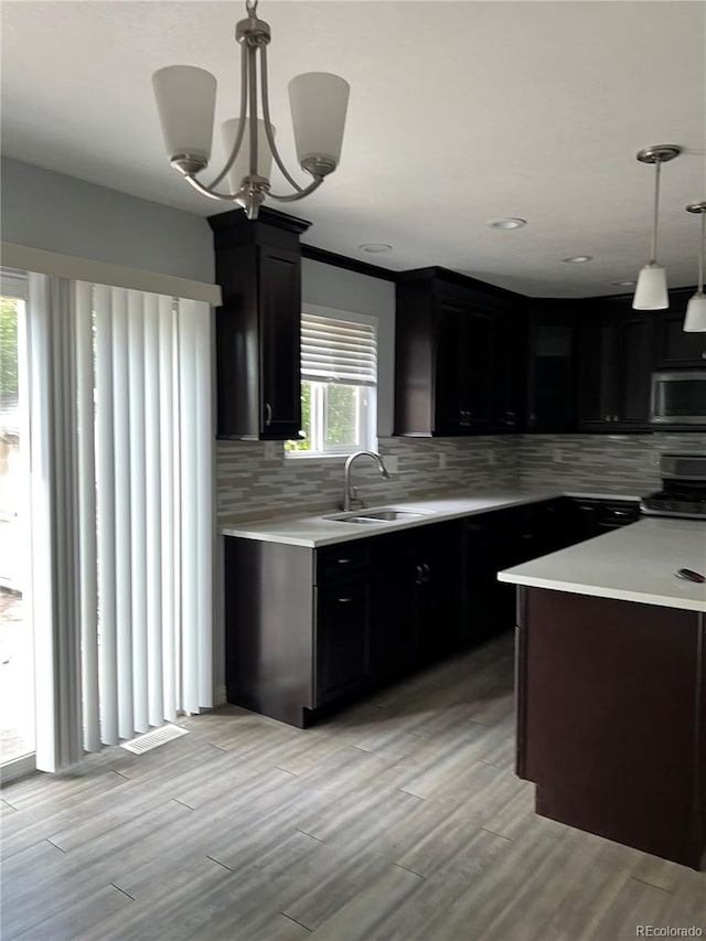 kitchen featuring backsplash, sink, a chandelier, pendant lighting, and light hardwood / wood-style flooring