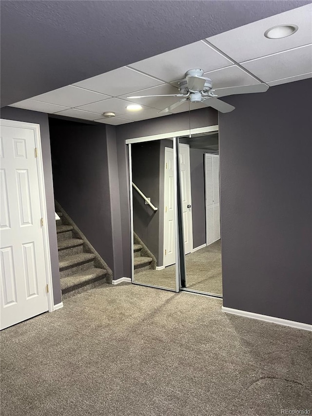 basement with ceiling fan, a paneled ceiling, and carpet