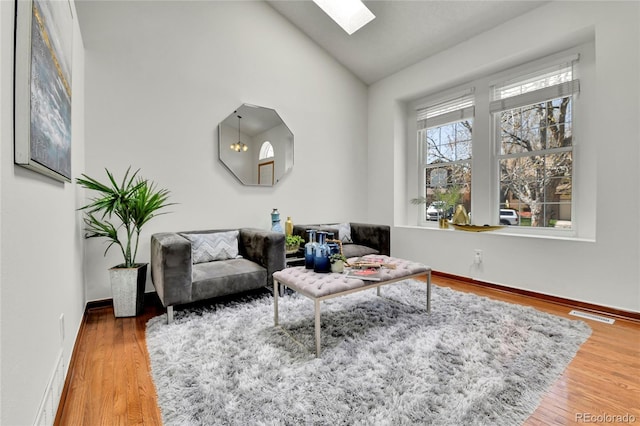 living area with a skylight, baseboards, wood finished floors, and visible vents