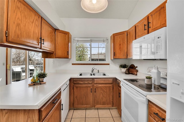 kitchen with a sink, brown cabinets, white appliances, and light countertops