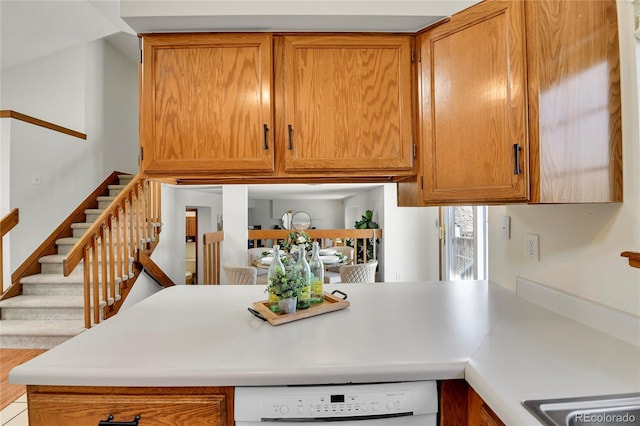 kitchen featuring brown cabinetry, light countertops, and dishwasher