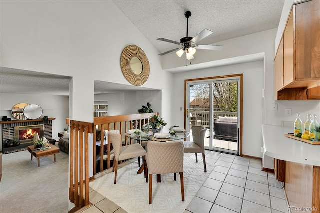 dining area featuring a brick fireplace, a ceiling fan, a textured ceiling, and light tile patterned floors