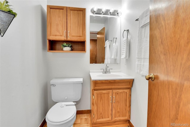half bath featuring baseboards, toilet, and vanity