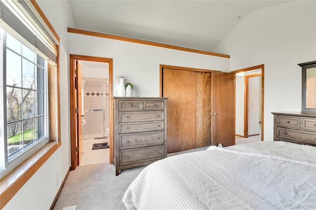 bedroom featuring light colored carpet, vaulted ceiling, ensuite bathroom, and a closet