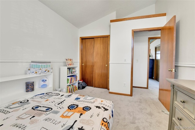 carpeted bedroom with a textured ceiling, vaulted ceiling, baseboards, and a closet