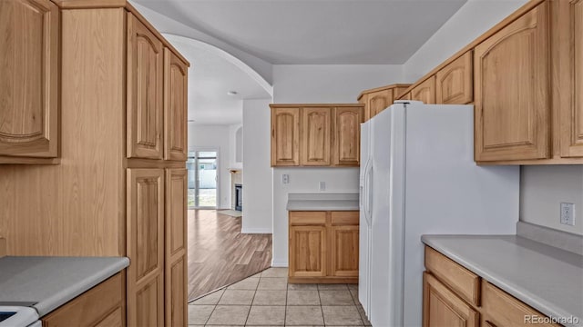 kitchen with white fridge with ice dispenser, light countertops, and light tile patterned flooring