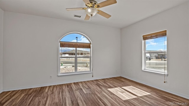 spare room featuring ceiling fan, wood finished floors, visible vents, and baseboards