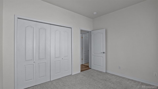 unfurnished bedroom with a closet, baseboards, and carpet flooring