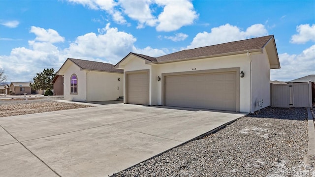 single story home with a garage, a gate, concrete driveway, and stucco siding