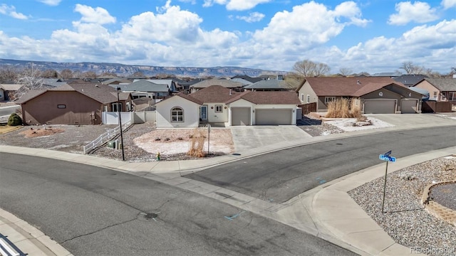 view of front facade featuring a garage, a residential view, fence, and driveway