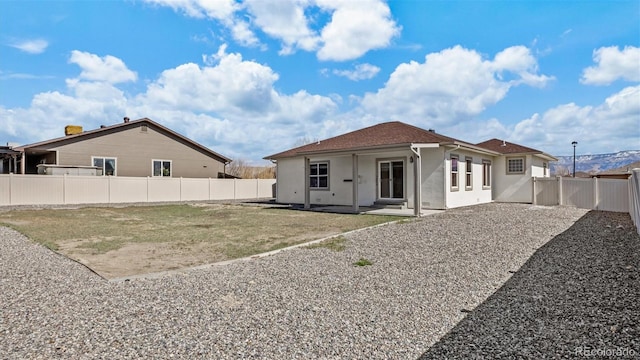 rear view of property with a patio area, a fenced backyard, a yard, and stucco siding