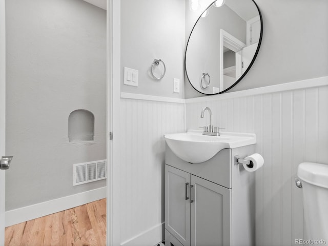 3630 Magnolia St, Denver, CO 80207 - bathroom with wainscoting, vanity, wood finished floors, and toilet