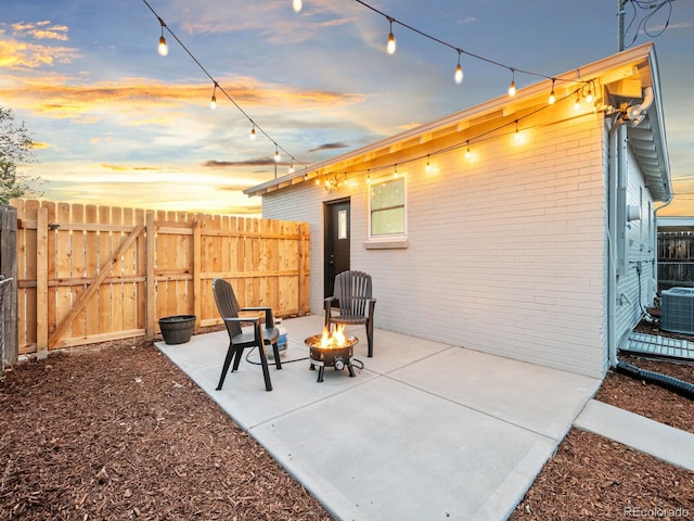 3630 Magnolia St, Denver, CO 80207 - patio terrace at dusk with an outdoor fire pit, fence, and central AC