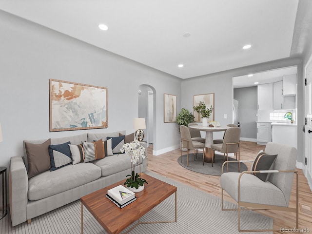 3630 Magnolia St, Denver, CO 80207 - living room featuring arched walkways, baseboards, recessed lighting, and light wood-style flooring