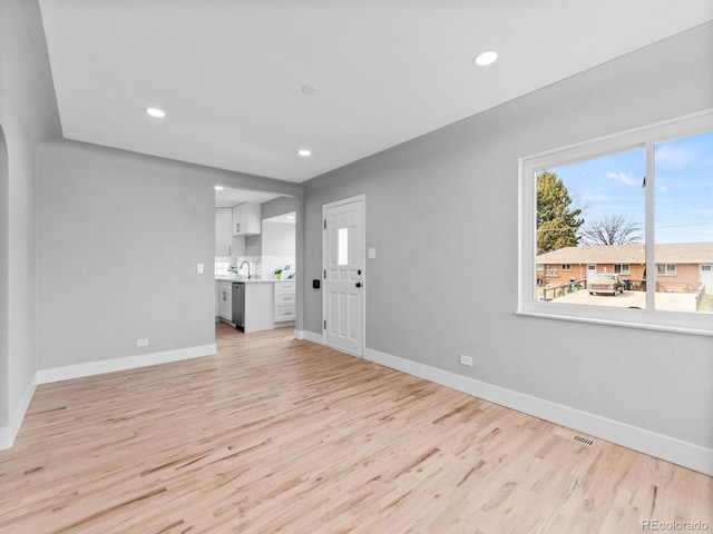 3630 Magnolia St, Denver, CO 80207 - unfurnished living room with light wood-style floors, baseboards, recessed lighting, and a sink