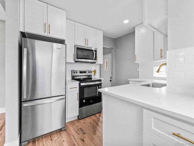 3630 Magnolia St, Denver, CO 80207 - kitchen featuring appliances with stainless steel finishes, a sink, white cabinets, light wood finished floors, and light countertops