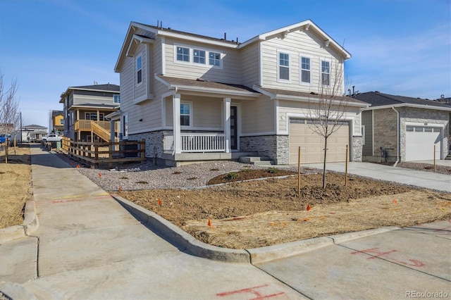 view of front of house featuring stone siding, covered porch, concrete driveway, and a garage