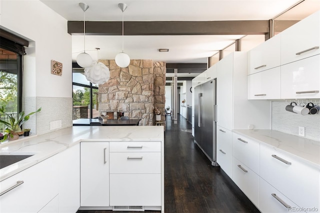 kitchen featuring dark wood finished floors, beam ceiling, light stone counters, and backsplash