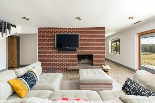 living area with baseboards, speckled floor, and a brick fireplace