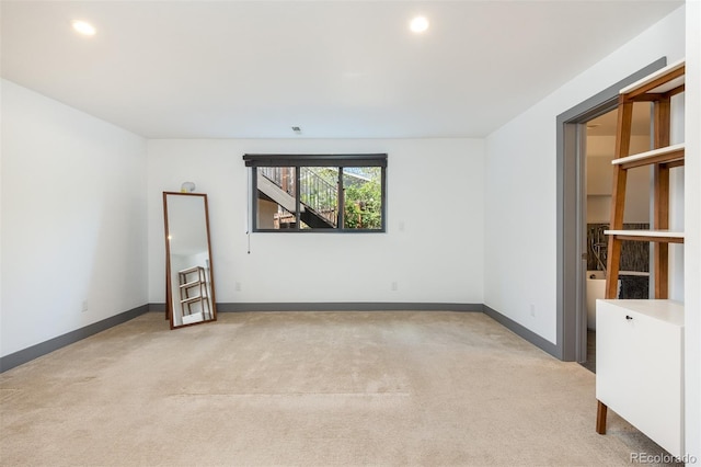 empty room featuring light carpet, recessed lighting, and baseboards