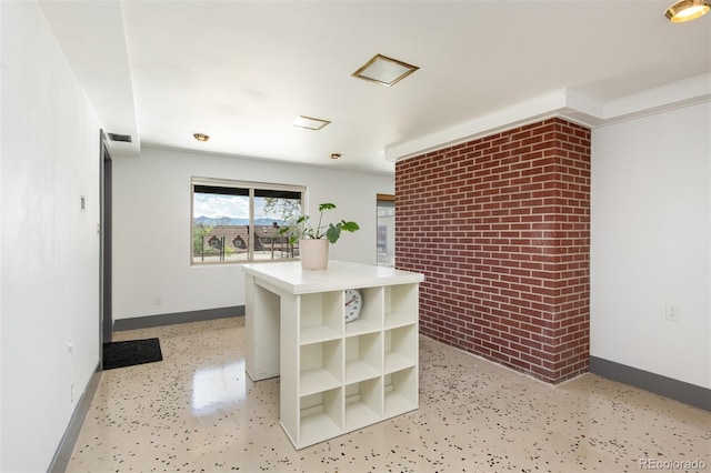 kitchen featuring baseboards, open shelves, light countertops, and brick wall