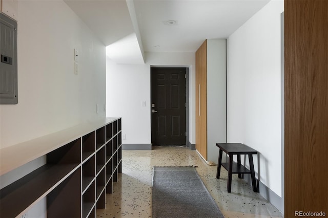 hall with baseboards, electric panel, and dark speckled floor