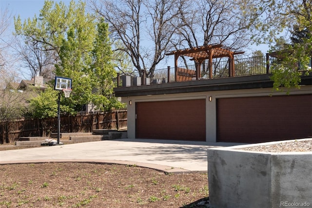 garage featuring concrete driveway and fence