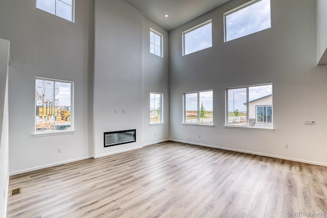 2197 S Jackson Gap St, Aurora, CO 80018 - unfurnished living room featuring a towering ceiling, wood finished floors, and a glass covered fireplace