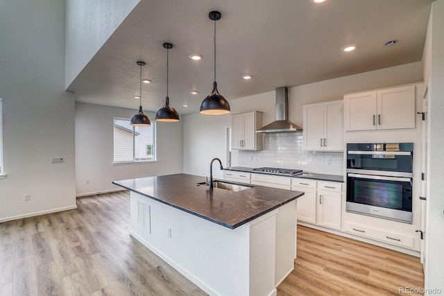 2197 S Jackson Gap St, Aurora, CO 80018 - kitchen featuring wall chimney exhaust hood, stainless steel appliances, light wood-style floors, white cabinets, and decorative backsplash