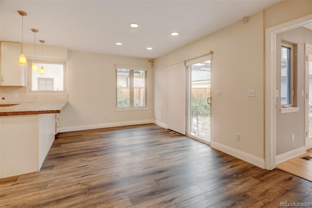 1275 Fairfax St, Denver, CO 80220 - kitchen featuring recessed lighting, wood finished floors, white cabinetry, decorative light fixtures, and decorative backsplash