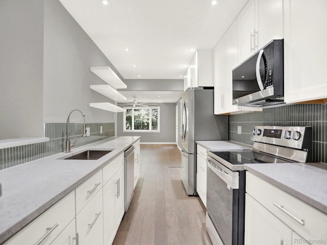 2046 S Quitman St, Denver, CO 80219 - kitchen featuring appliances with stainless steel finishes, light wood-style floors, tasteful backsplash, white cabinets, and ceiling fan