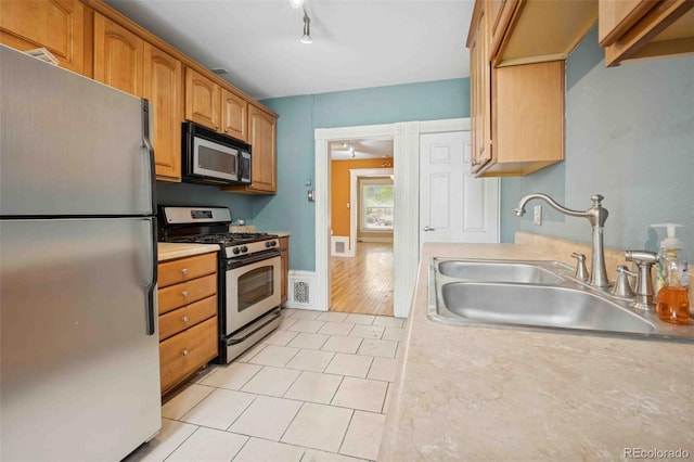 709 27th St, Denver, CO 80205 - kitchen featuring stainless steel appliances, a sink, light tile patterned flooring, light countertops, and brown cabinets