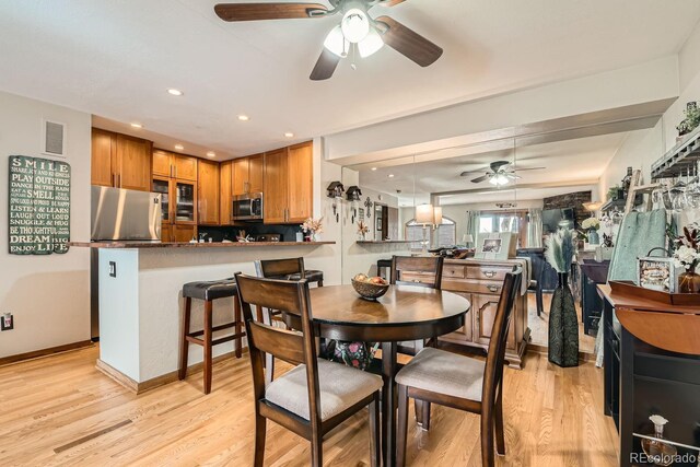 dining space with light hardwood / wood-style floors and ceiling fan