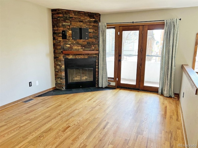 611 E 7th Ave, Denver, CO 80203 - unfurnished living room with visible vents, baseboards, wood finished floors, and a stone fireplace