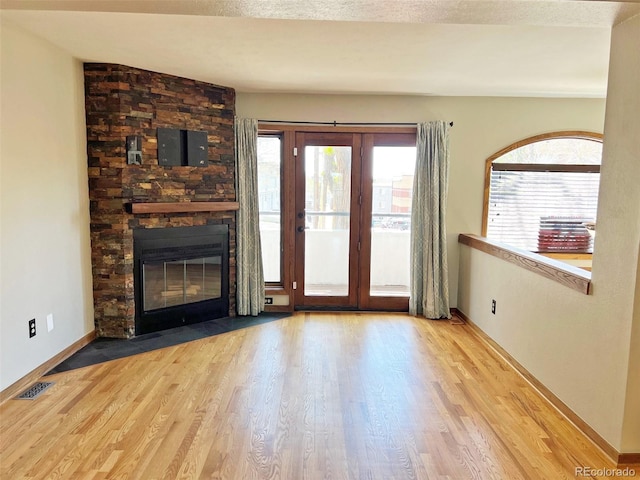 611 E 7th Ave, Denver, CO 80203 - unfurnished living room featuring a stone fireplace, baseboards, wood finished floors, and visible vents