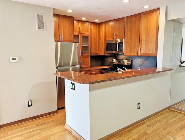 611 E 7th Ave, Denver, CO 80203 - kitchen featuring brown cabinets, stainless steel appliances, visible vents, and light wood-style flooring