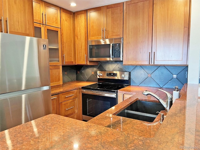 611 E 7th Ave, Denver, CO 80203 - kitchen with brown cabinets, light stone counters, a sink, backsplash, and stainless steel appliances