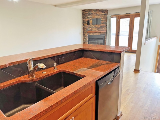 611 E 7th Ave, Denver, CO 80203 - kitchen featuring a stone fireplace, light wood-type flooring, a sink, and dishwasher