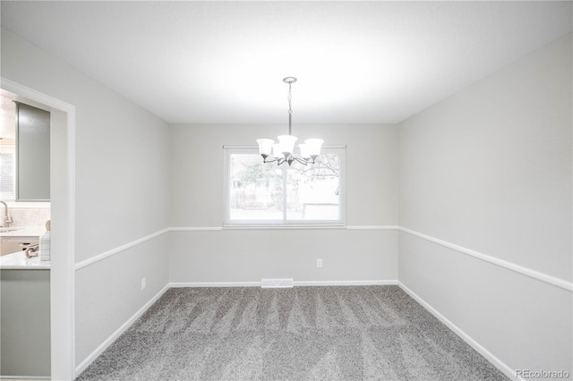 empty room with baseboards, visible vents, carpet floors, an inviting chandelier, and a sink